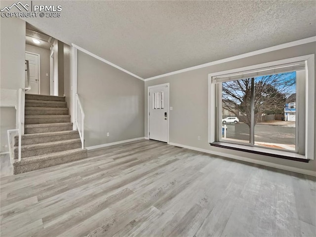 unfurnished living room with ornamental molding, a textured ceiling, and light hardwood / wood-style floors