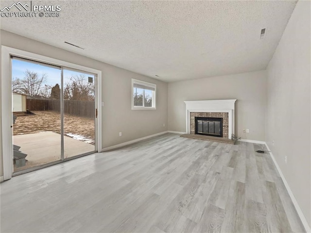 unfurnished living room with a textured ceiling, light wood-type flooring, and a fireplace