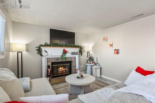 living room featuring a fireplace, wood-type flooring, and a textured ceiling