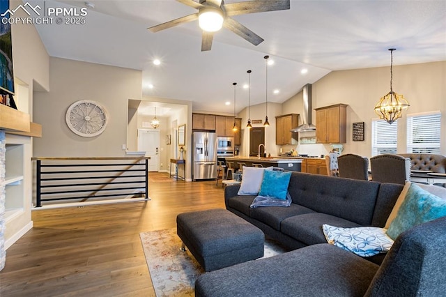 living room with wood-type flooring, lofted ceiling, sink, and ceiling fan with notable chandelier