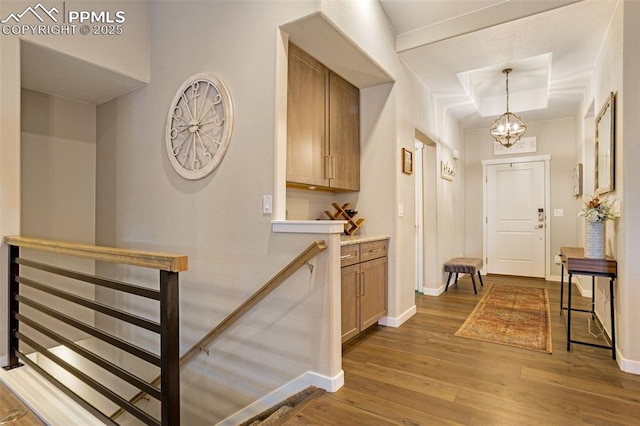 corridor featuring an inviting chandelier, a tray ceiling, and hardwood / wood-style floors