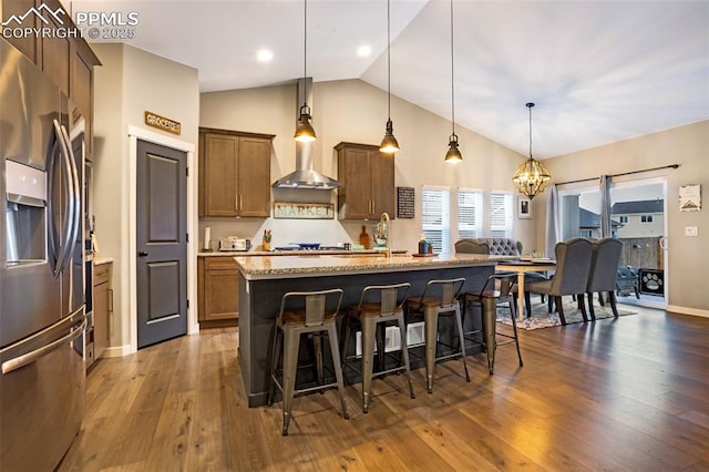 kitchen with appliances with stainless steel finishes, a kitchen island with sink, a breakfast bar area, and decorative light fixtures