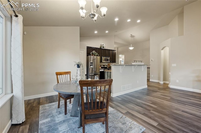 dining area with dark wood-type flooring, a notable chandelier, and high vaulted ceiling