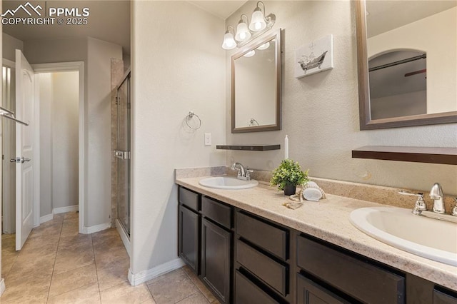 bathroom with a shower with door, vanity, and tile patterned floors