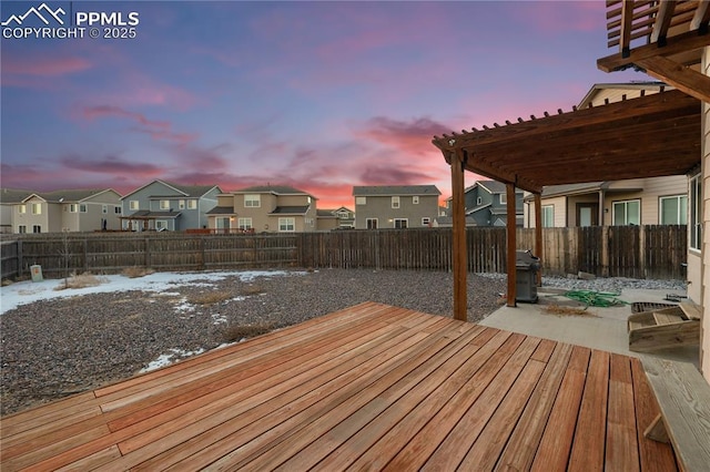 deck at dusk featuring area for grilling, a pergola, and a patio