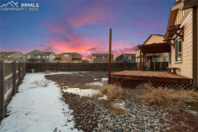 yard layered in snow with a wooden deck and a pergola