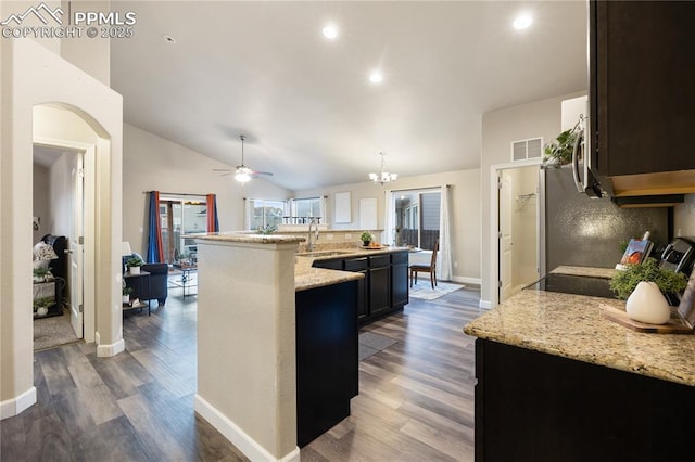 kitchen featuring light stone counters, sink, dark hardwood / wood-style floors, and a center island with sink