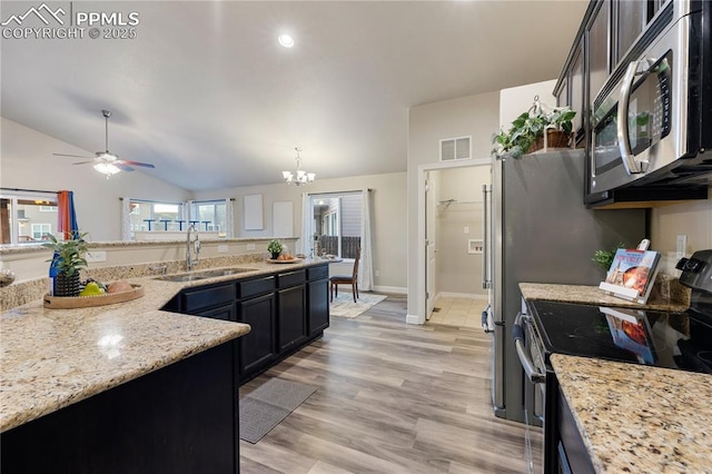 kitchen featuring lofted ceiling, sink, appliances with stainless steel finishes, pendant lighting, and light stone countertops