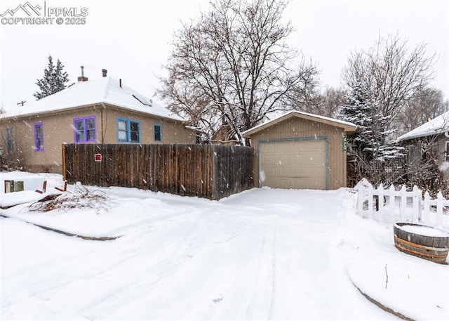 view of snow covered exterior featuring an outbuilding and a garage