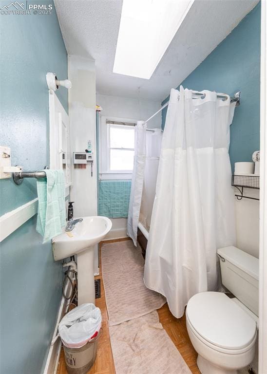 bathroom featuring hardwood / wood-style floors, a textured ceiling, a skylight, and toilet