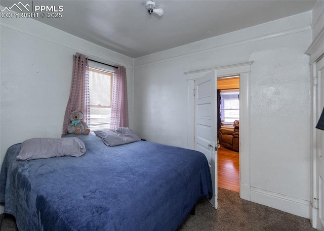 bedroom featuring multiple windows and dark colored carpet