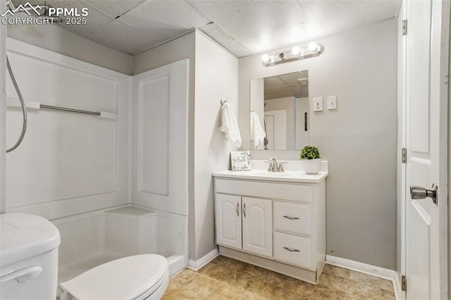 bathroom with walk in shower, vanity, toilet, and a drop ceiling