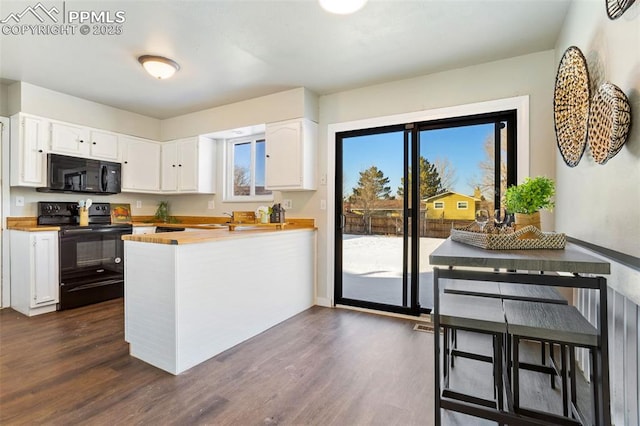 kitchen with white cabinetry, dark hardwood / wood-style flooring, kitchen peninsula, and black appliances