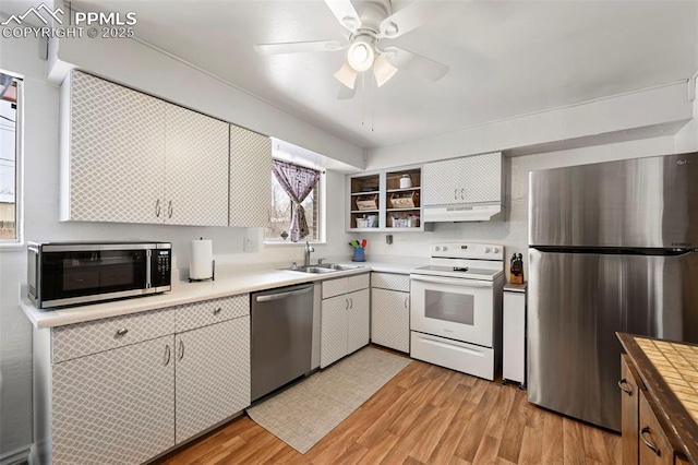 kitchen featuring appliances with stainless steel finishes, white cabinetry, sink, ceiling fan, and light wood-type flooring