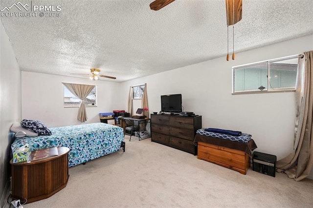 bedroom with ceiling fan, carpet floors, and a textured ceiling