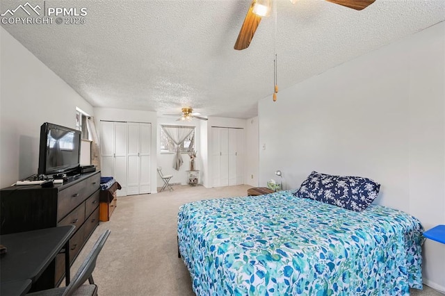 carpeted bedroom with ceiling fan, two closets, and a textured ceiling