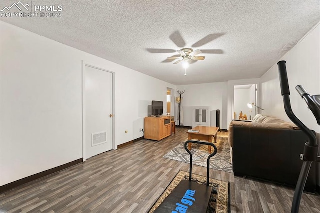 living room featuring hardwood / wood-style flooring, ceiling fan, and a textured ceiling