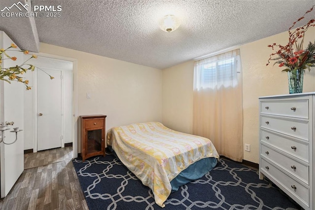 bedroom with dark hardwood / wood-style floors and a textured ceiling