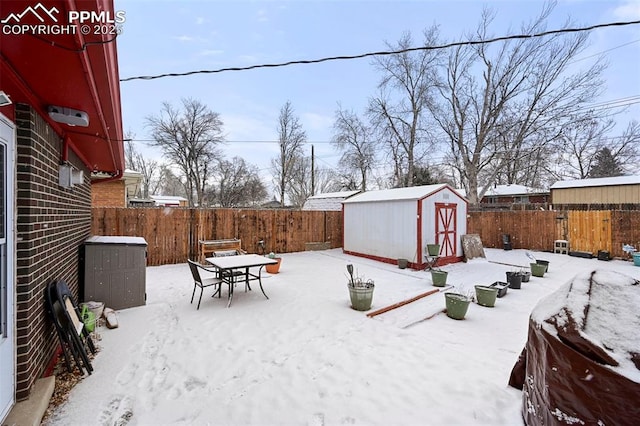 yard layered in snow featuring a storage shed