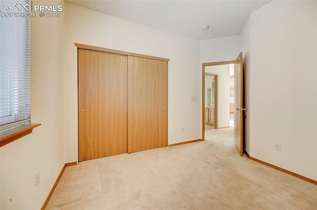 unfurnished bedroom featuring light colored carpet and a closet