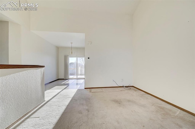 carpeted spare room featuring an inviting chandelier