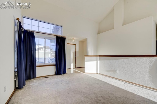 carpeted empty room with high vaulted ceiling