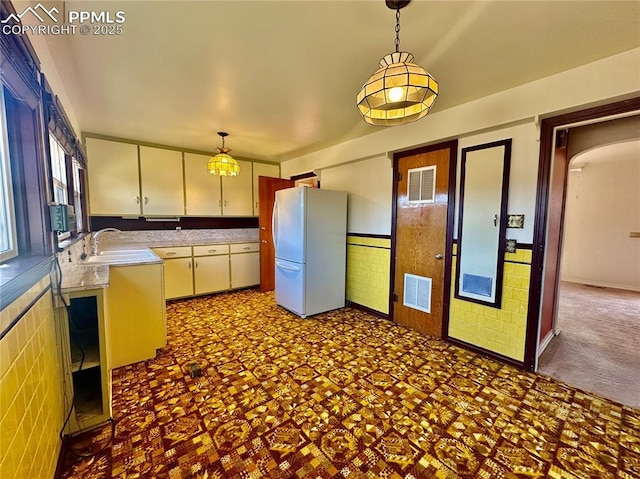 kitchen featuring white refrigerator, dark colored carpet, sink, and pendant lighting