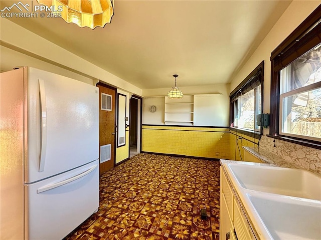 kitchen featuring french doors, sink, tile walls, white fridge, and pendant lighting