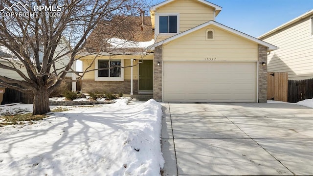 view of front of house with driveway, brick siding, an attached garage, and fence