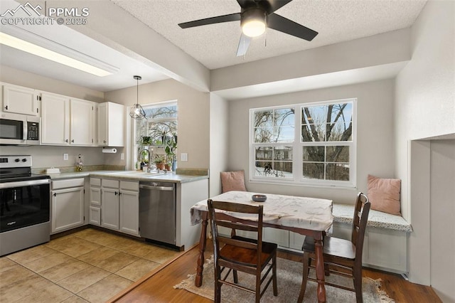 kitchen featuring stainless steel appliances, sink, hanging light fixtures, a healthy amount of sunlight, and white cabinets