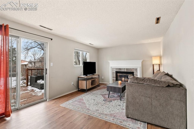 living room featuring plenty of natural light, a fireplace, hardwood / wood-style floors, and a textured ceiling