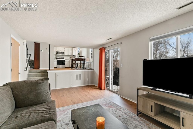 living room with a textured ceiling and light wood-type flooring