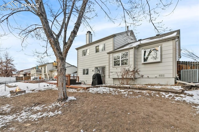 snow covered rear of property featuring a deck and central air condition unit