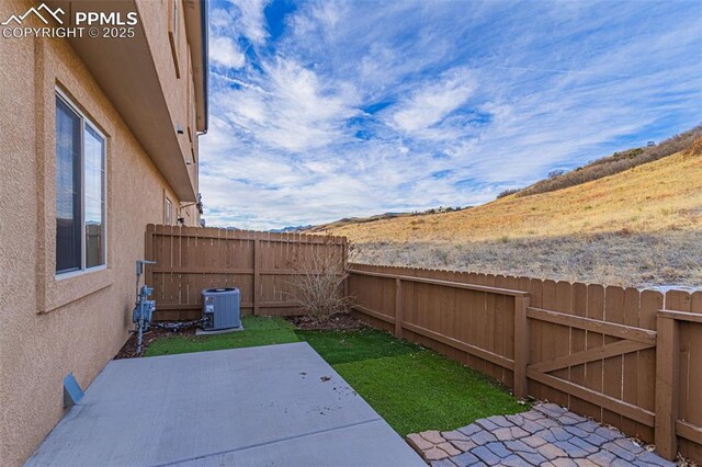 view of yard with central air condition unit and a patio area