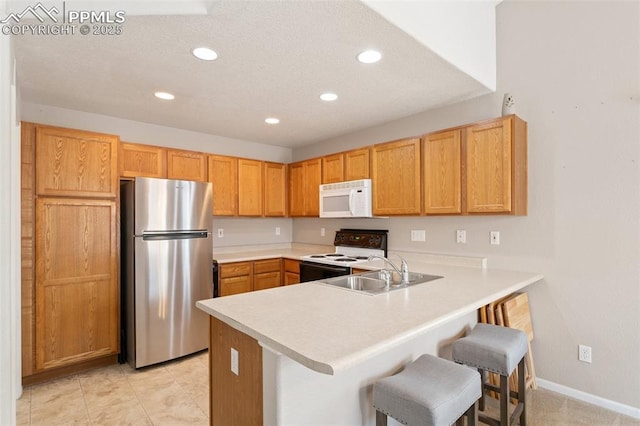 kitchen with range with electric stovetop, sink, a breakfast bar area, stainless steel fridge, and kitchen peninsula