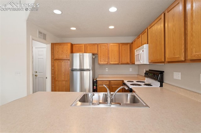 kitchen with stainless steel refrigerator, sink, and range with electric stovetop