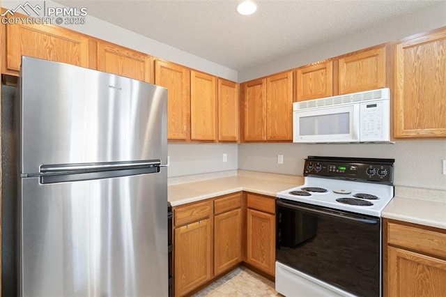 kitchen featuring stainless steel fridge, electric range oven, and a textured ceiling