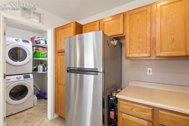 clothes washing area with stacked washer and dryer and a textured ceiling