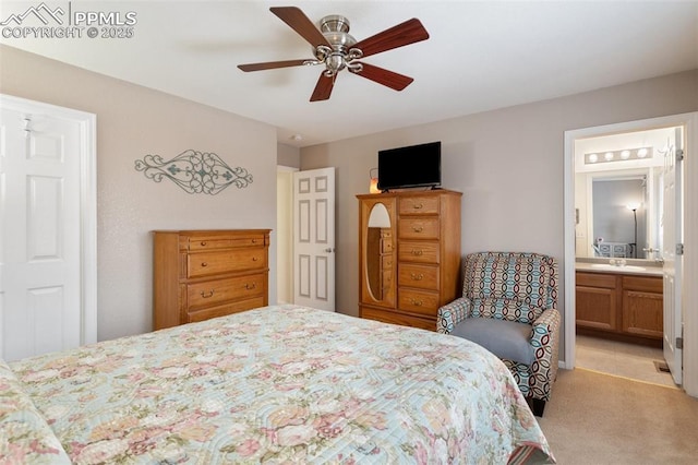 bedroom featuring ceiling fan, sink, light colored carpet, and ensuite bath