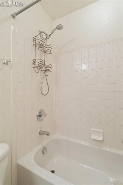 bathroom with toilet and tiled shower / bath combo