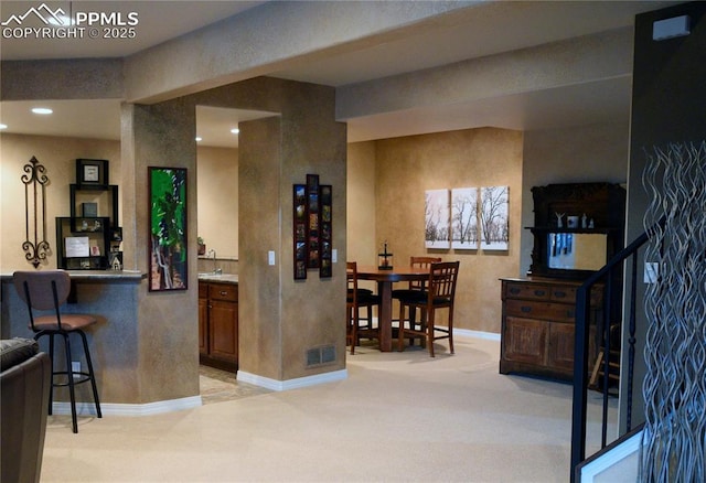 kitchen featuring sink, a breakfast bar area, and light carpet