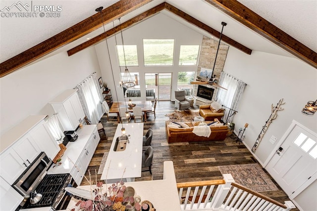 living room with dark wood-type flooring, a stone fireplace, high vaulted ceiling, a notable chandelier, and beam ceiling