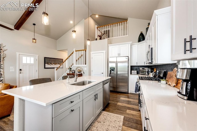 kitchen featuring sink, decorative light fixtures, high vaulted ceiling, an island with sink, and stainless steel appliances