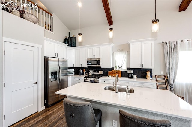 kitchen with sink, hanging light fixtures, appliances with stainless steel finishes, beamed ceiling, and white cabinets