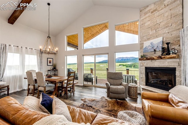 living room featuring dark wood-type flooring, high vaulted ceiling, a mountain view, a stone fireplace, and a chandelier