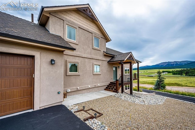 back of property with a mountain view and a garage