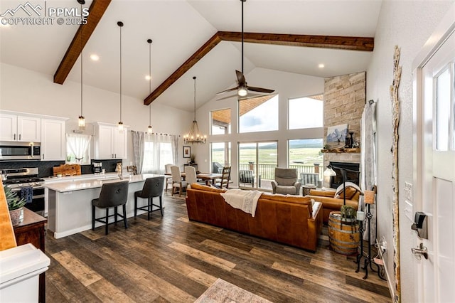 living room featuring dark hardwood / wood-style flooring, a stone fireplace, plenty of natural light, and high vaulted ceiling