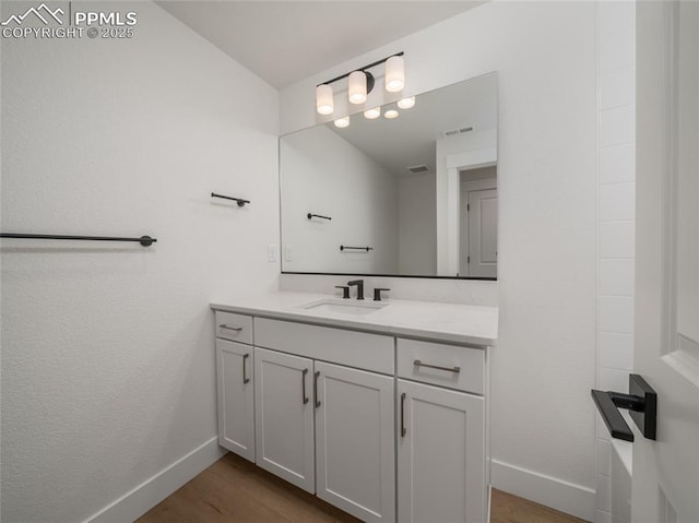 bathroom with baseboards, vanity, wood finished floors, and visible vents