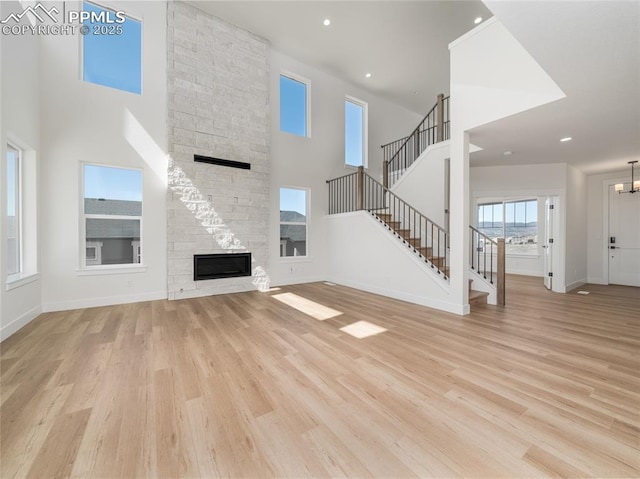 unfurnished living room featuring a high ceiling, wood finished floors, stairs, and baseboards