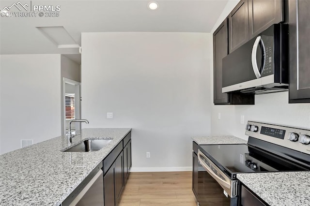 241 N Front St Unit 101, Monument, CO 80132 - kitchen with a sink, light wood finished floors, baseboards, appliances with stainless steel finishes, and light stone countertops
